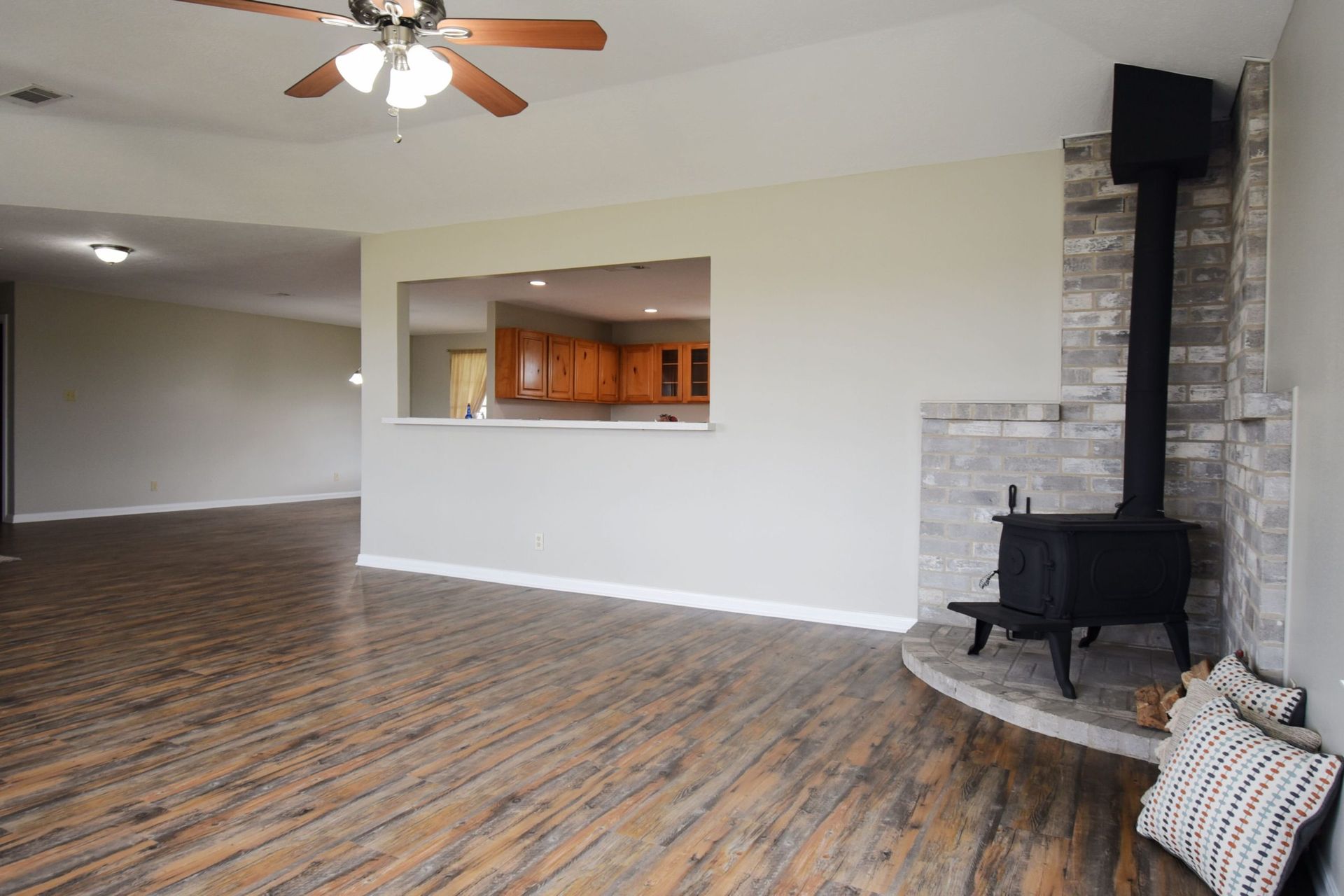 Living room with wood floors, a fireplace, and an open kitchen area.