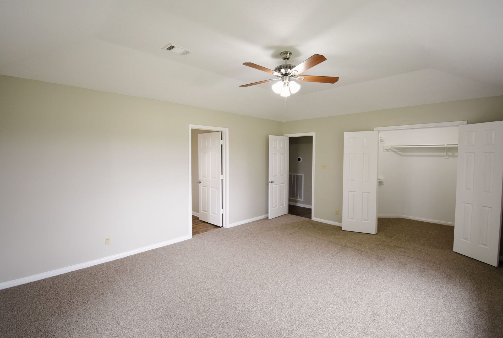 Empty bedroom with carpet, neutral walls, closet, and ceiling fan.