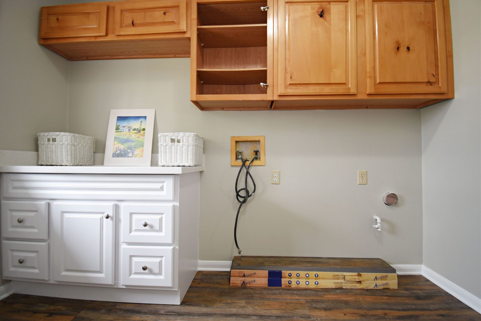 Laundry room with white cabinets, wooden flooring, beige walls, and empty wall-mounted cabinets.