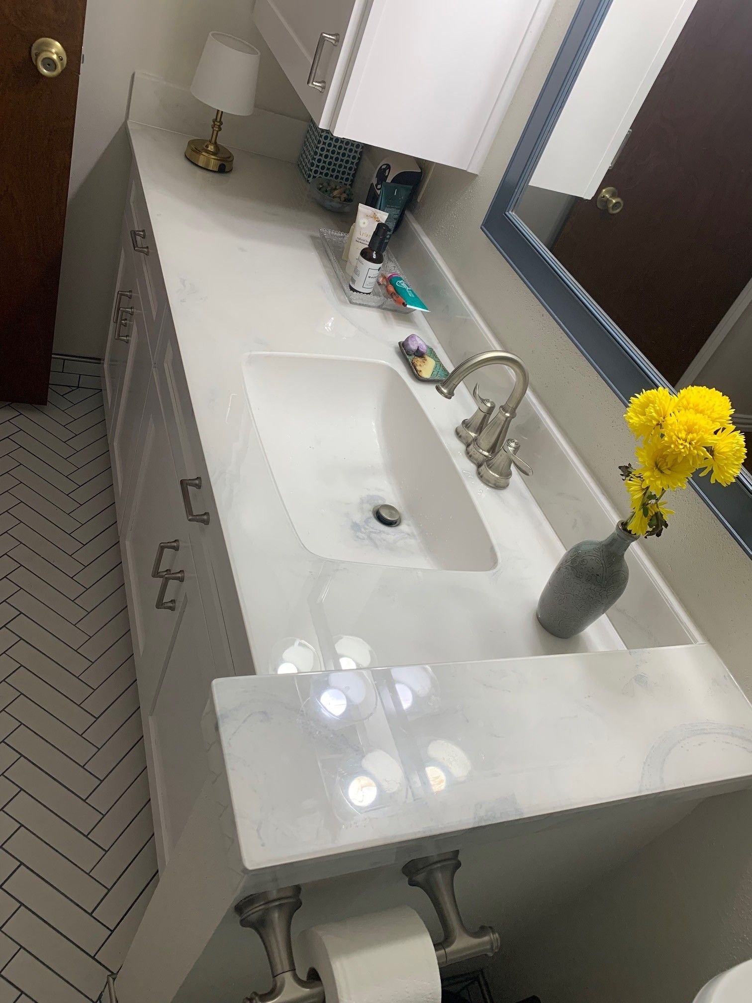 White bathroom vanity with a sink, gray countertop, and yellow flowers.