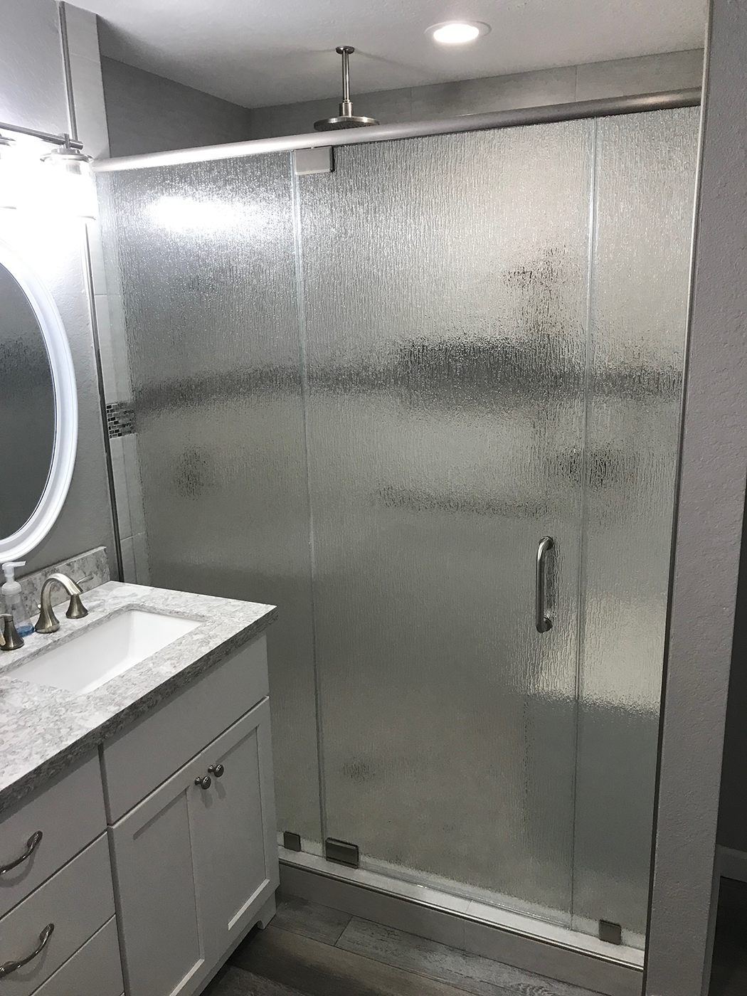Bathroom with a frosted glass shower door, white vanity, and silver fixtures.