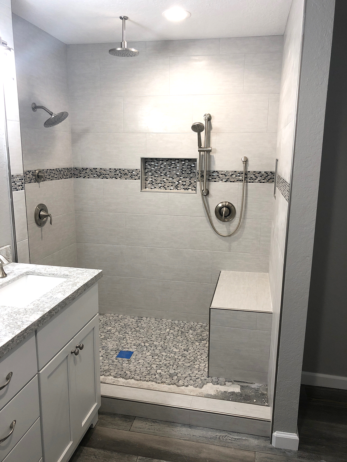 Modern bathroom with tiled shower and bench, with pebble flooring and granite vanity.