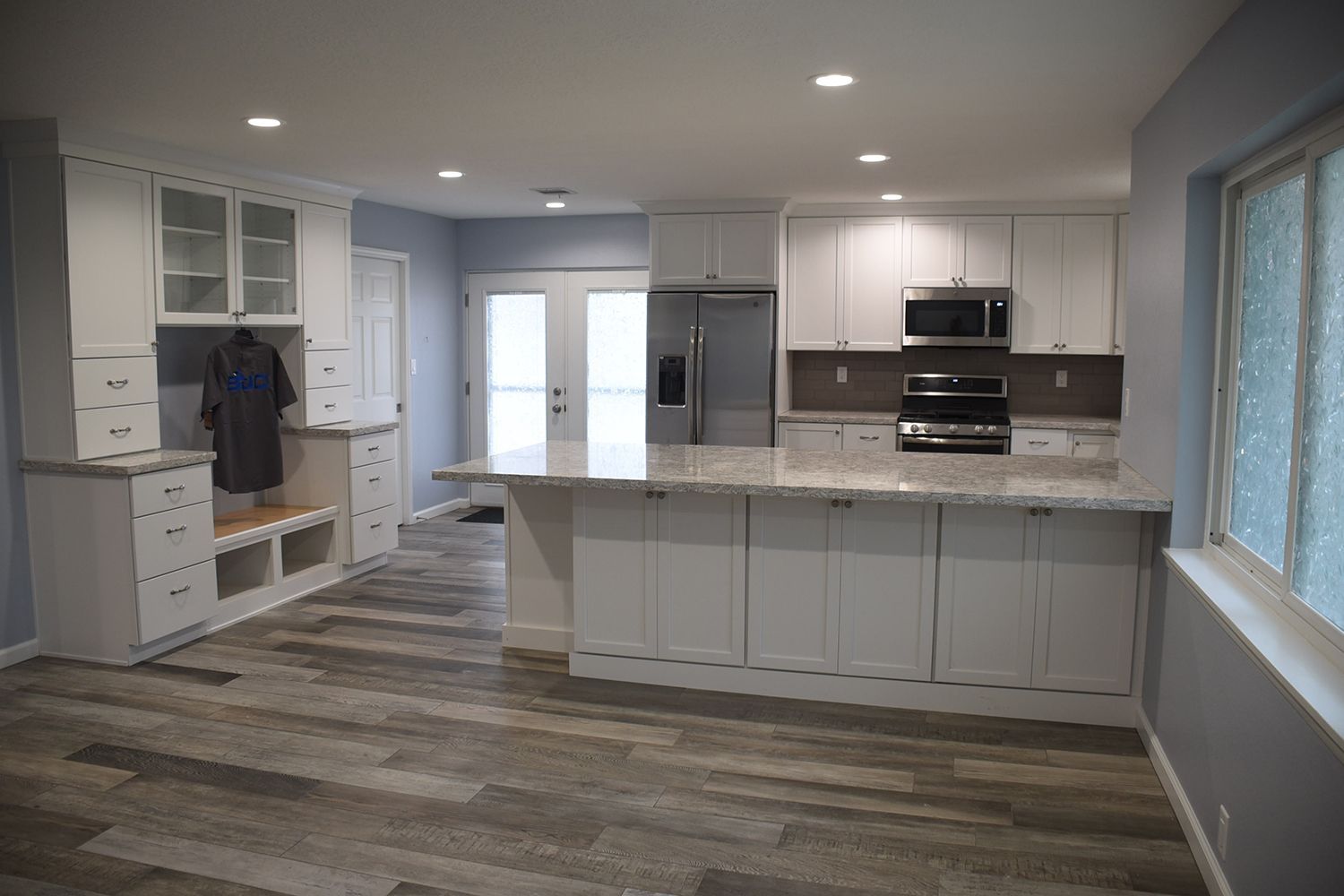 Newly renovated kitchen with white cabinets, gray countertops, and wood-look flooring.