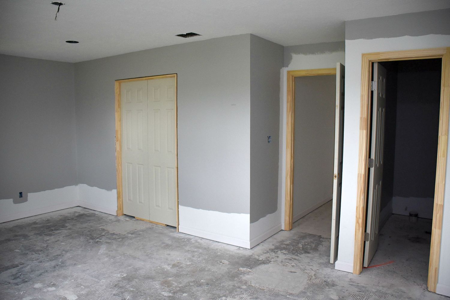 Gray painted interior room with unfinished concrete floor and doorways.