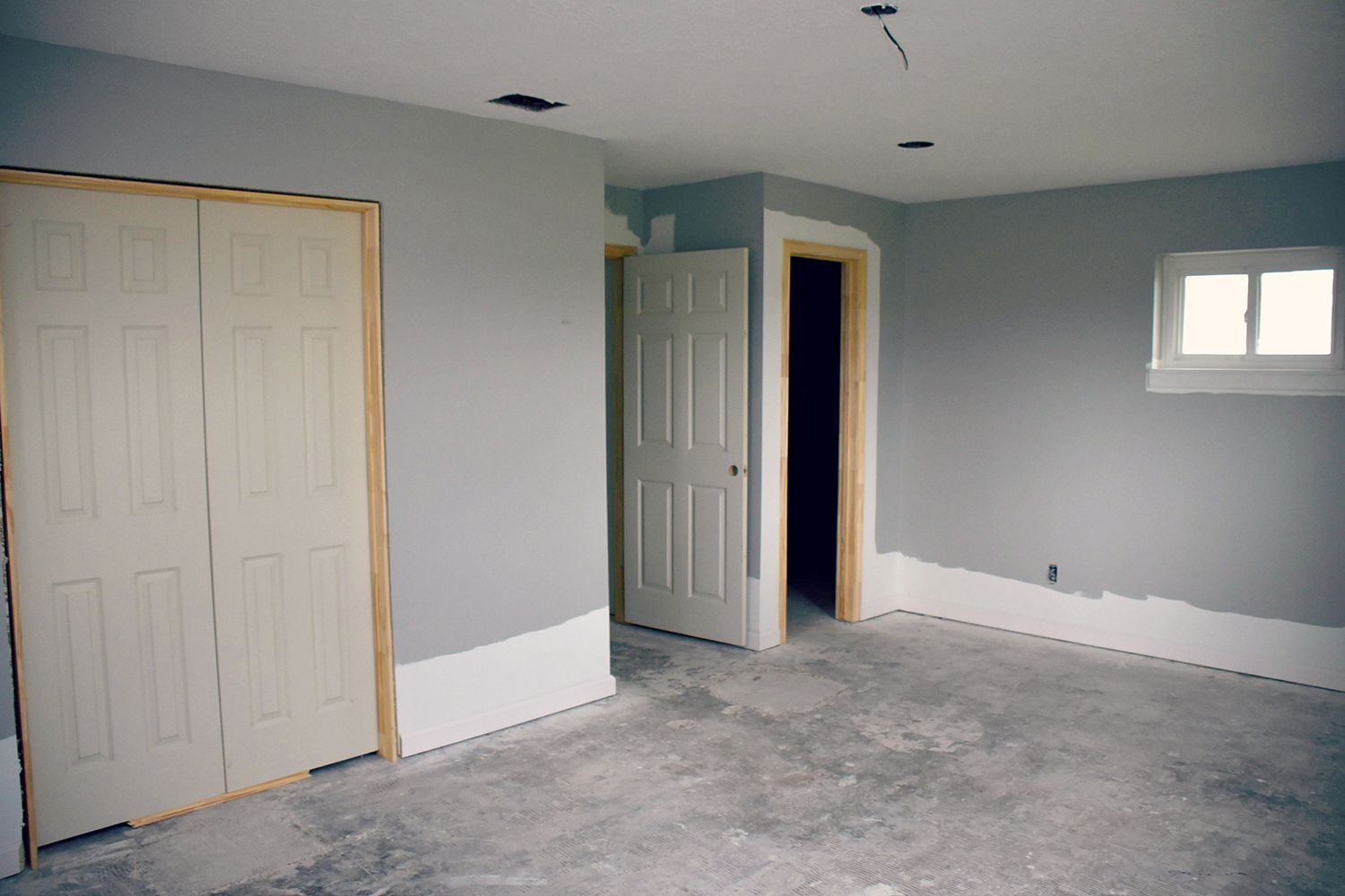 Empty room with gray walls, white trim, closet, and door frames.