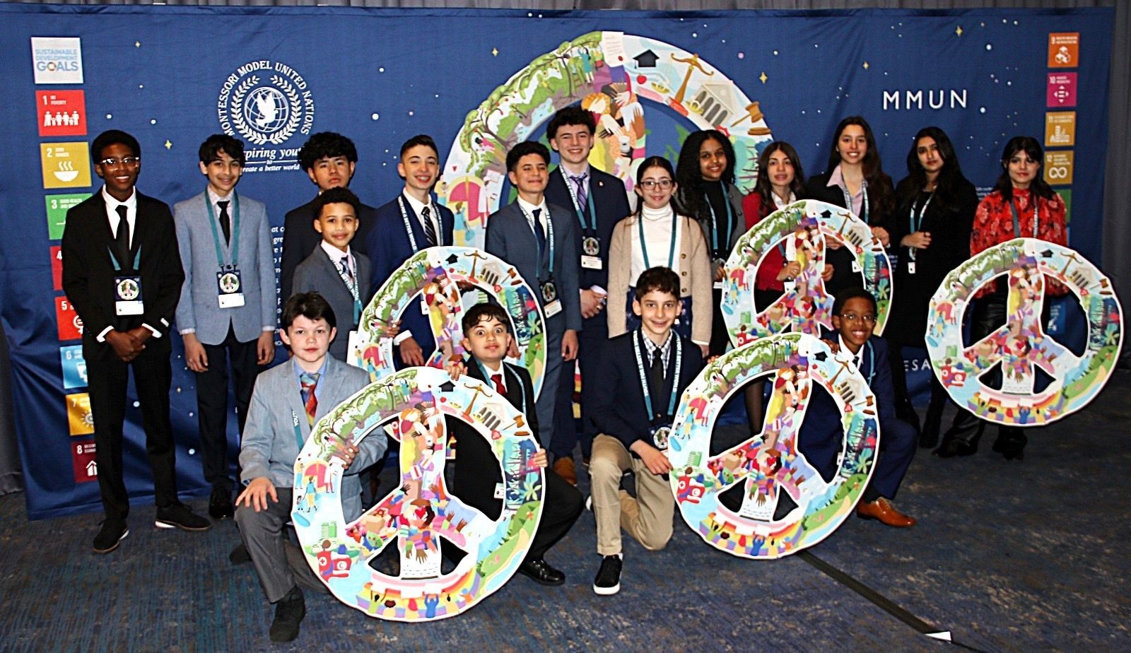 Group of people posing with large peace signs and colorful circular displays at a conference backdrop