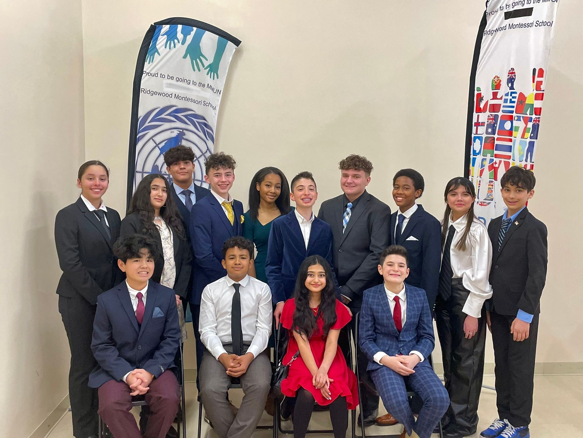 Group of students posing indoors in formal attire in front of banners.