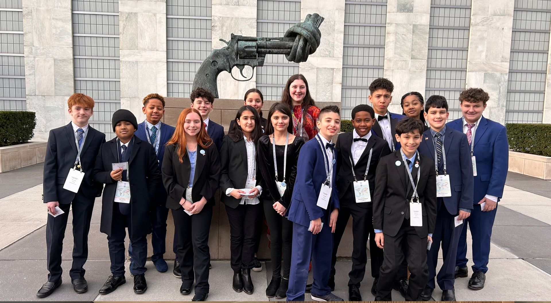 Group of students in formal uniforms posing outside, with a large assembly hall shown below.