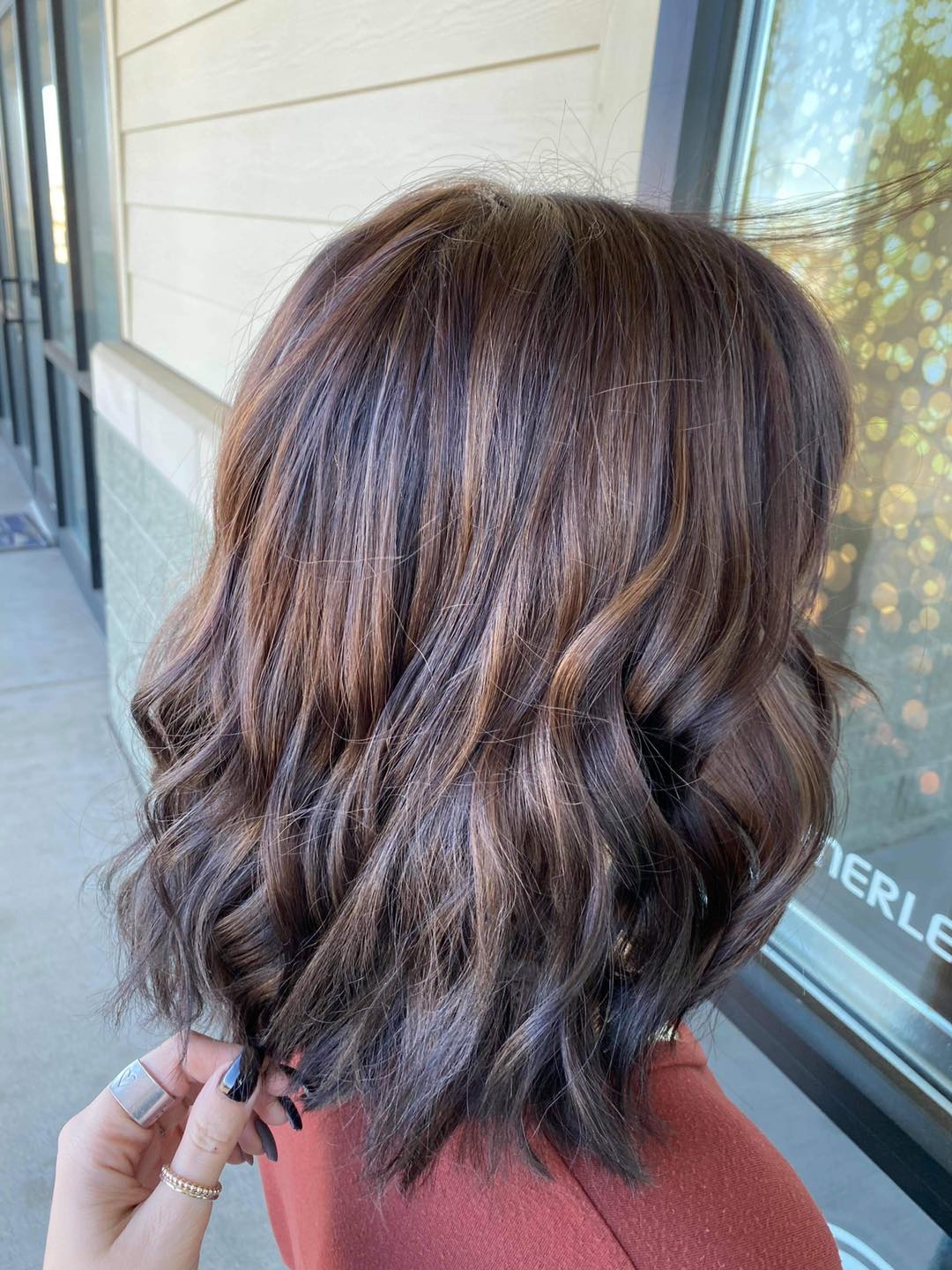 A woman with brown hair is standing in front of a building.