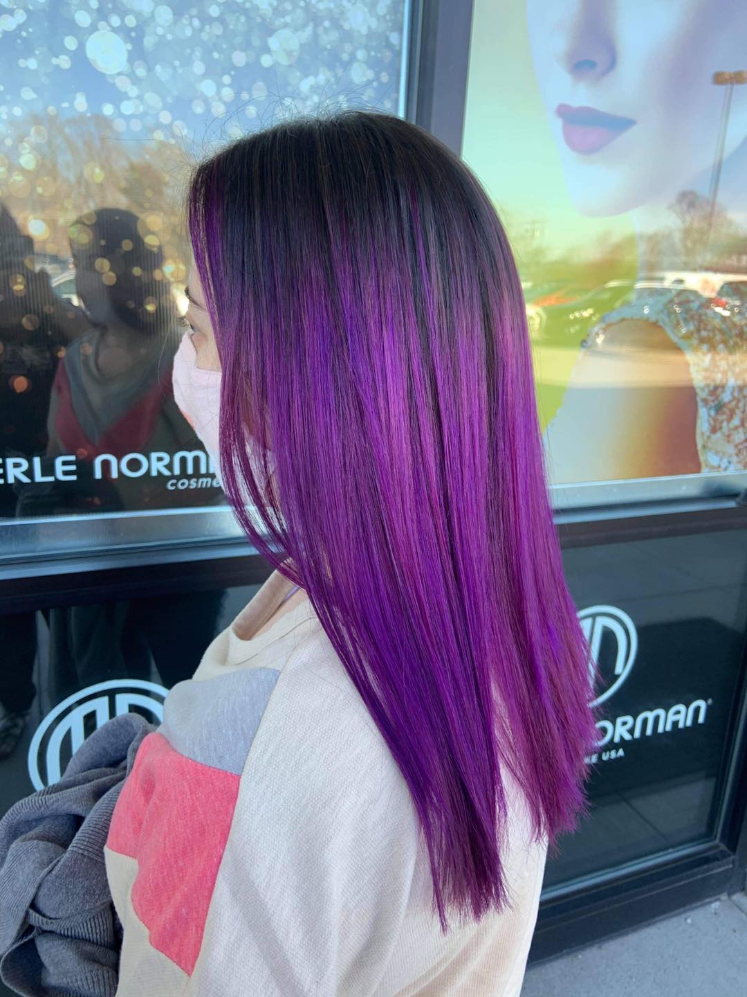 A woman with purple hair is wearing a mask.