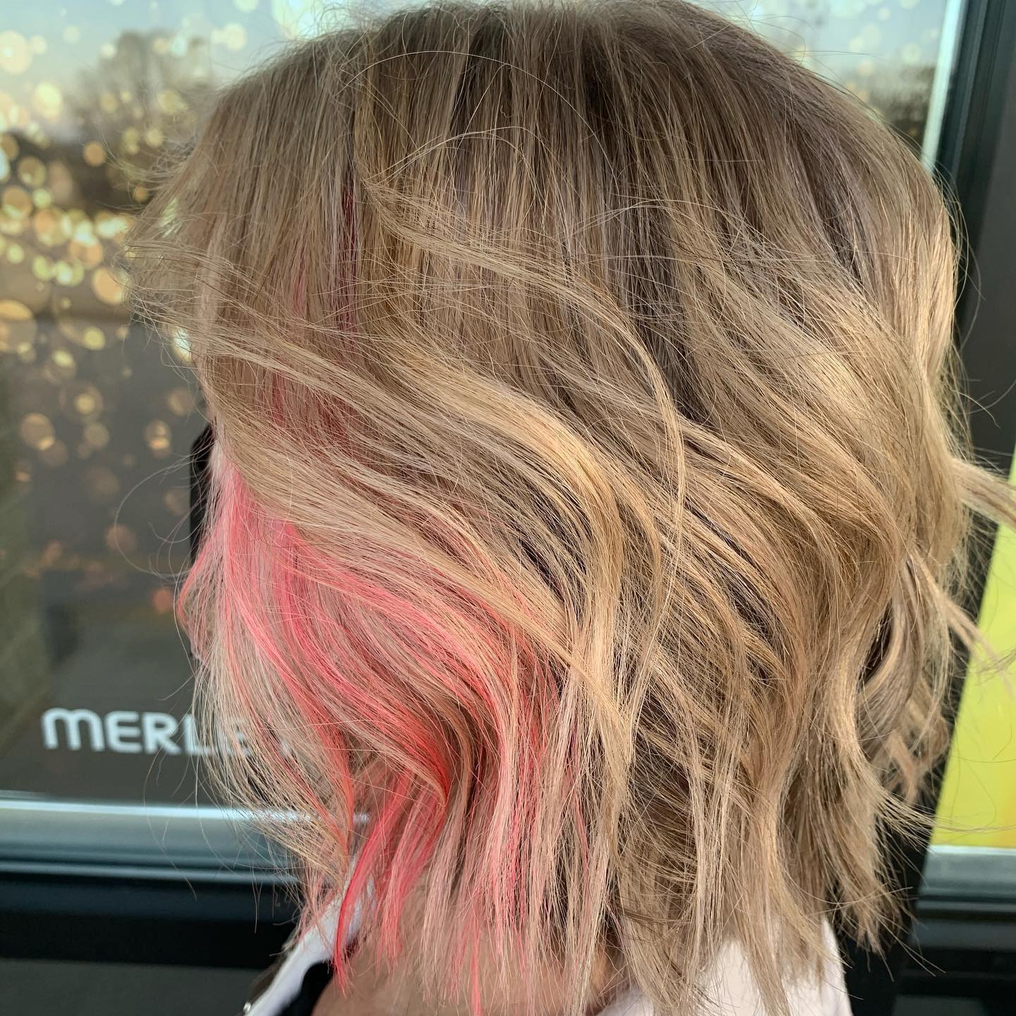 A close up of a person 's hair with pink highlights.