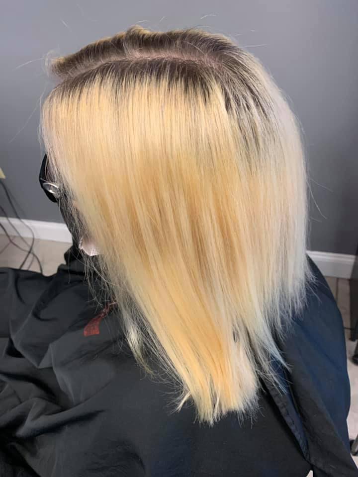 A woman with blonde hair is sitting in a chair getting her hair cut.