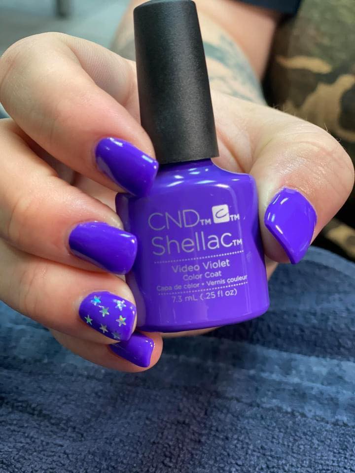 A person is holding a bottle of cnd shellac nail polish