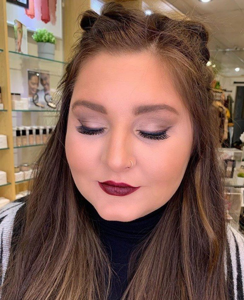 A close up of a woman 's face with makeup and a nose ring.