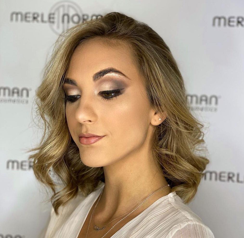 A woman is wearing a white shirt and a necklace.