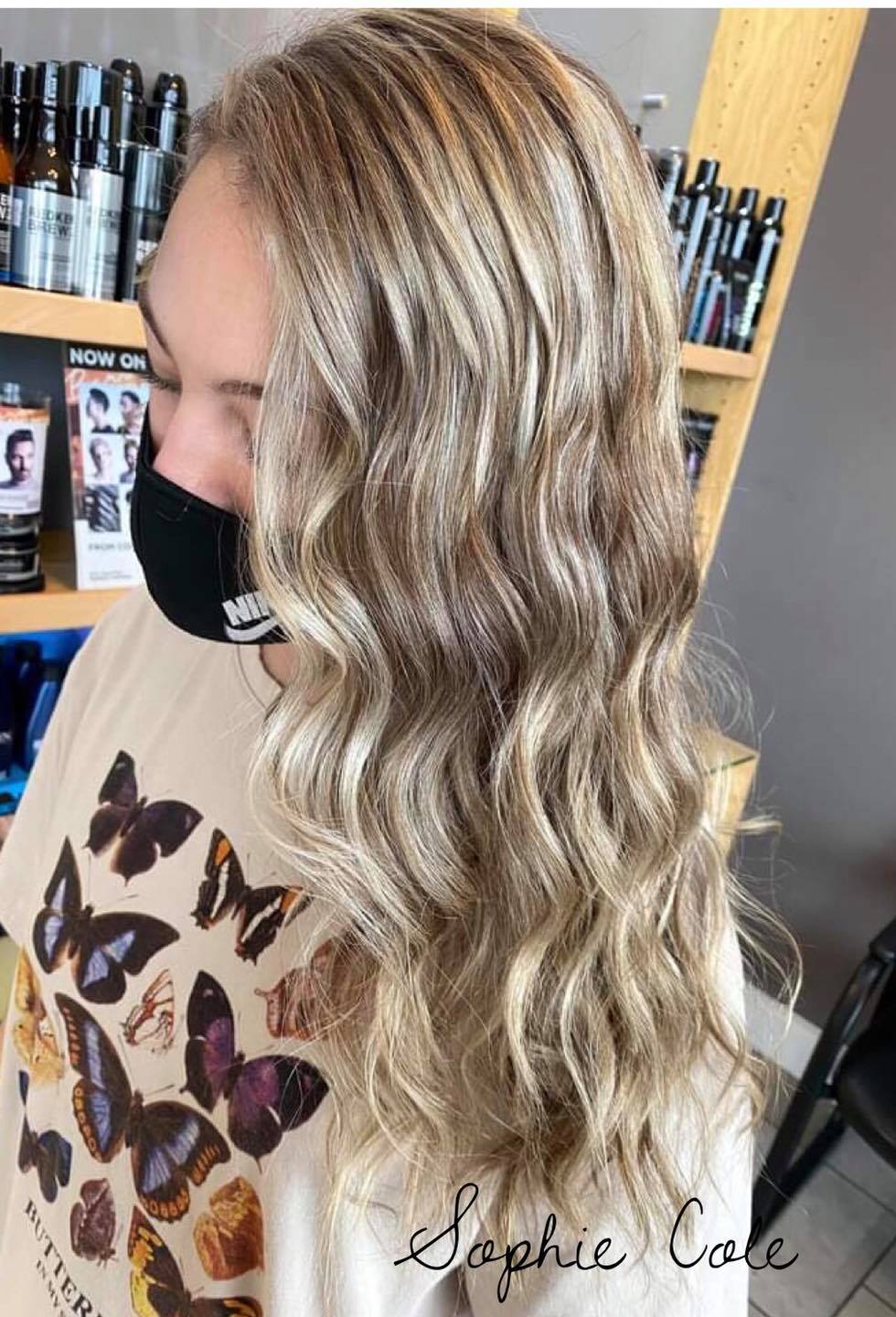 A woman wearing a mask and a shirt with butterflies on it.