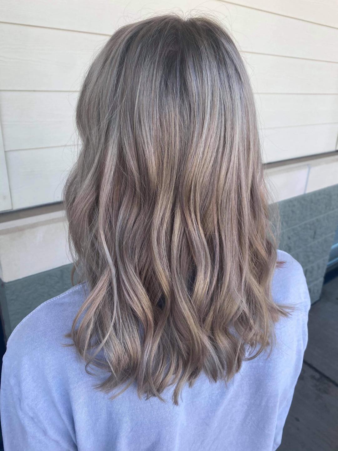 A woman with blonde hair is wearing a blue shirt and sitting on a couch.
