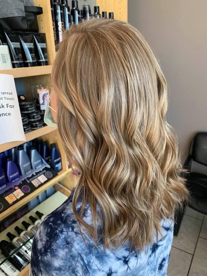 A woman with blonde hair is standing in front of a shelf of hair products.