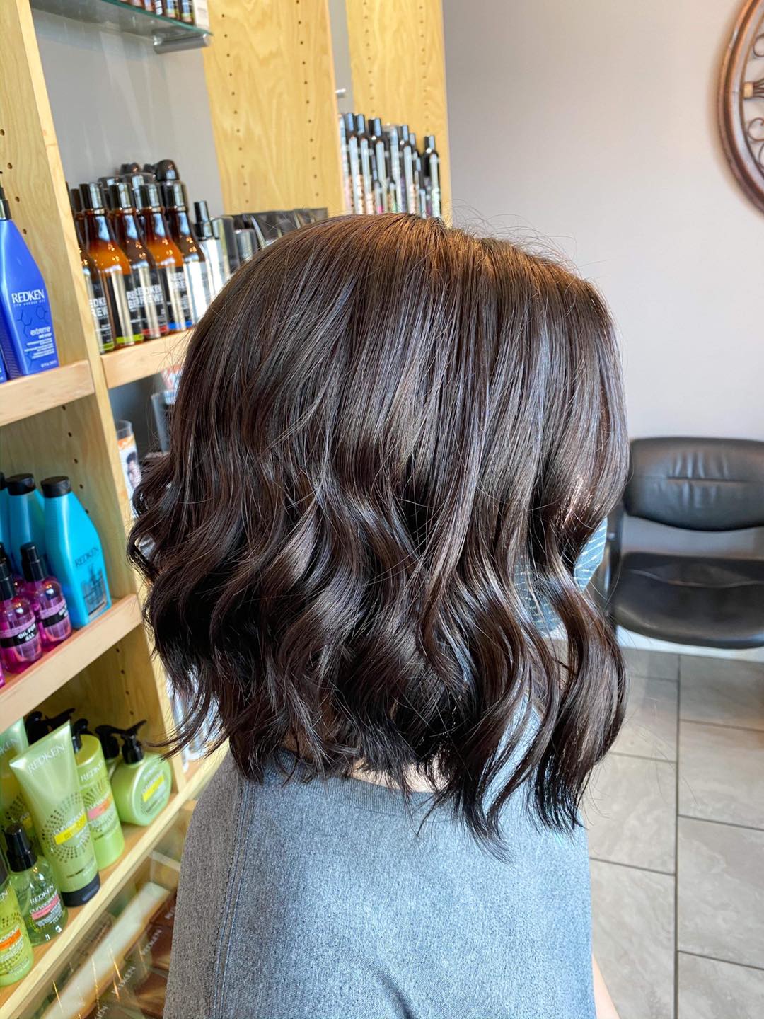 A woman with short brown hair is standing in a salon.