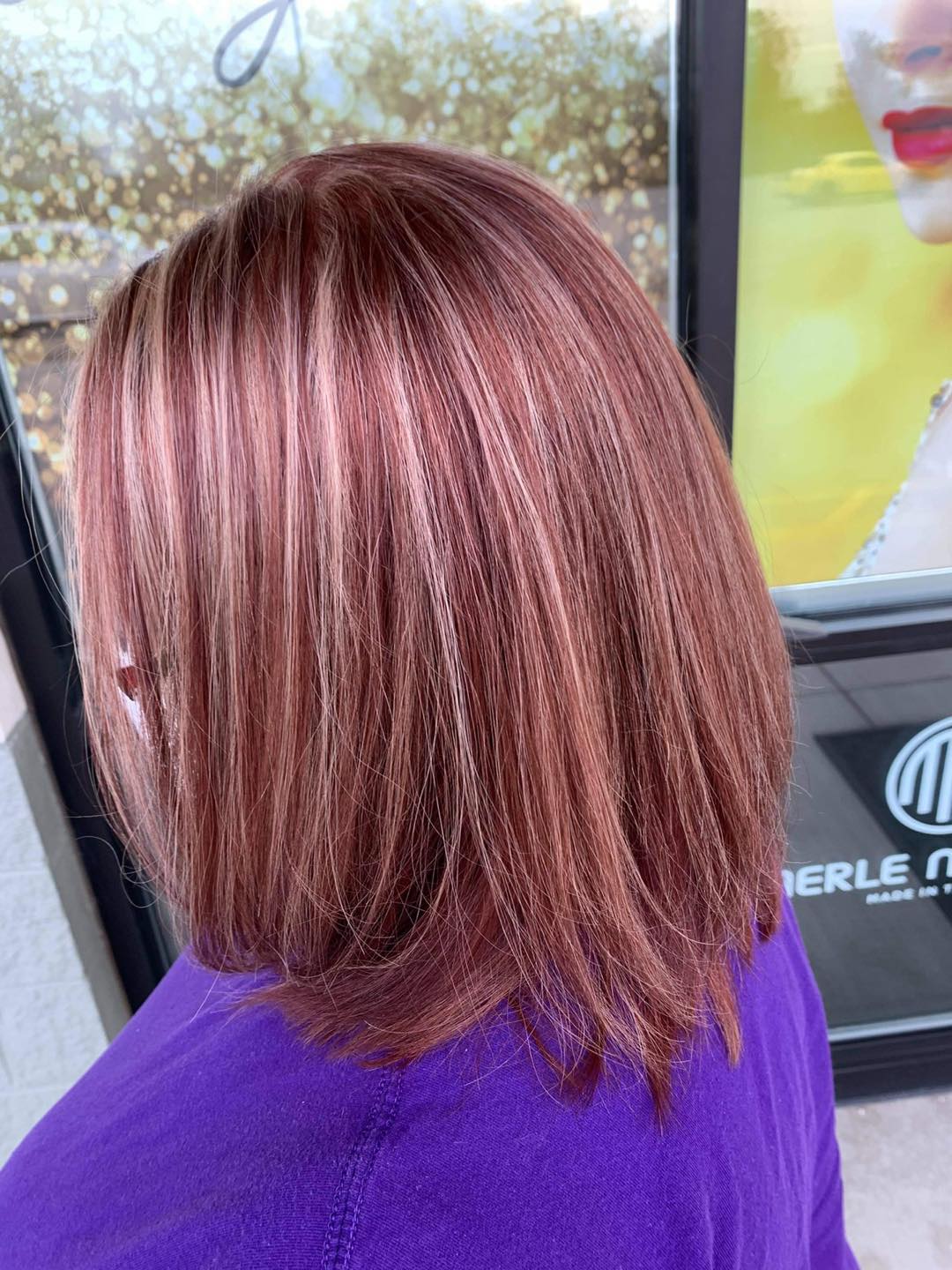 A woman with red hair is wearing a purple shirt.