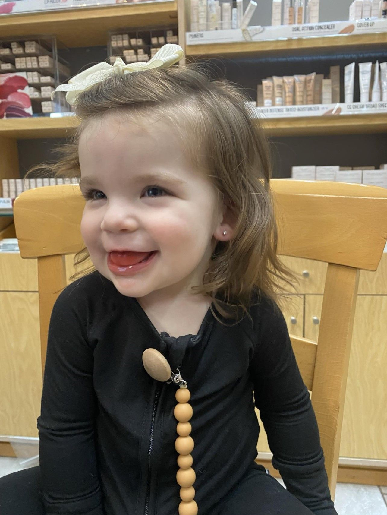 A little girl is sitting in a chair in a store and smiling.