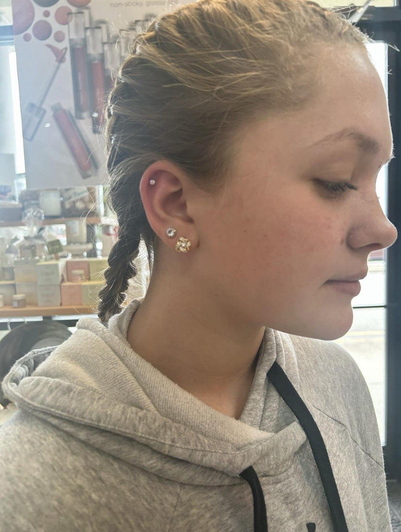 A woman wearing a hoodie and earrings is looking down
