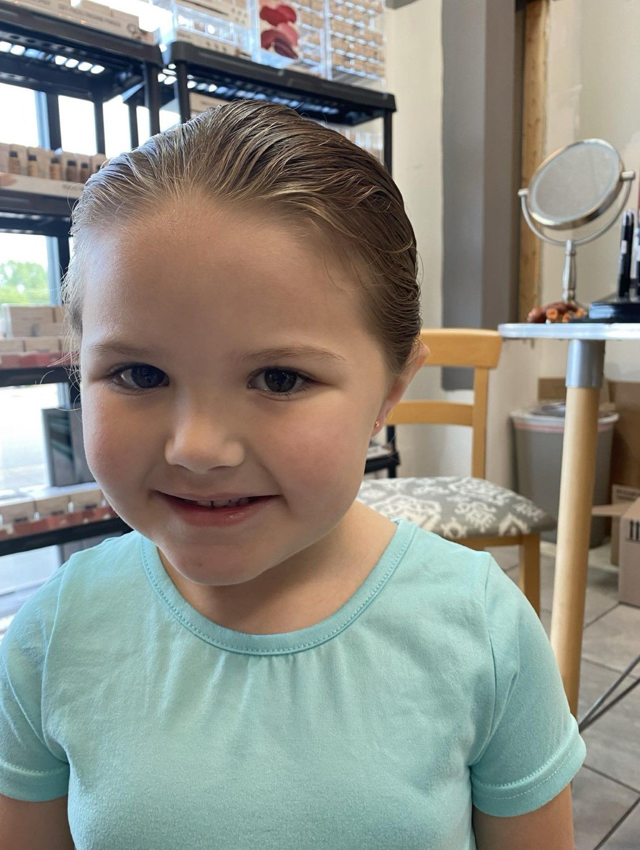 A little girl is sitting in front of a mirror in a room.