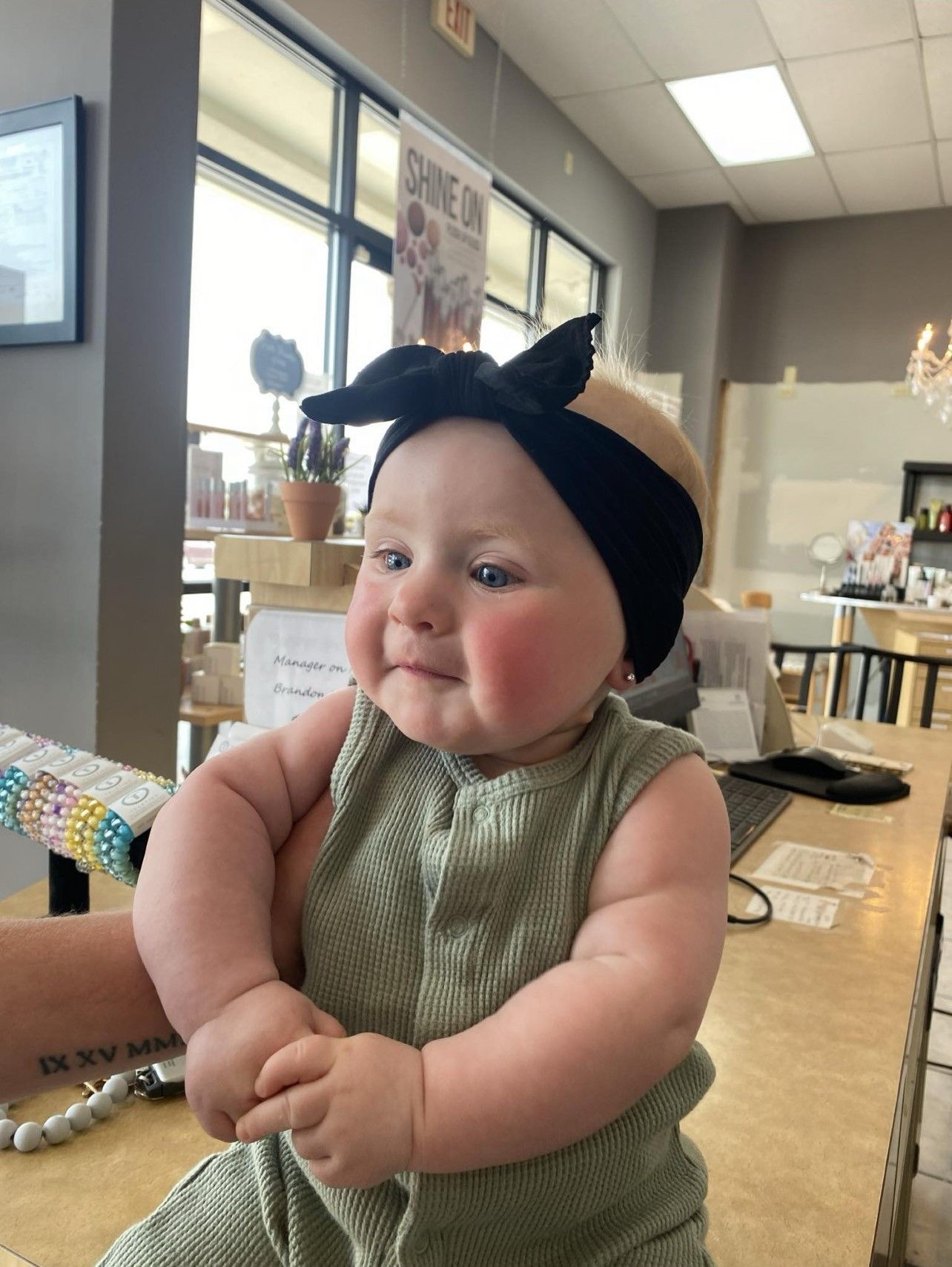 A baby is sitting at a table wearing a black headband.