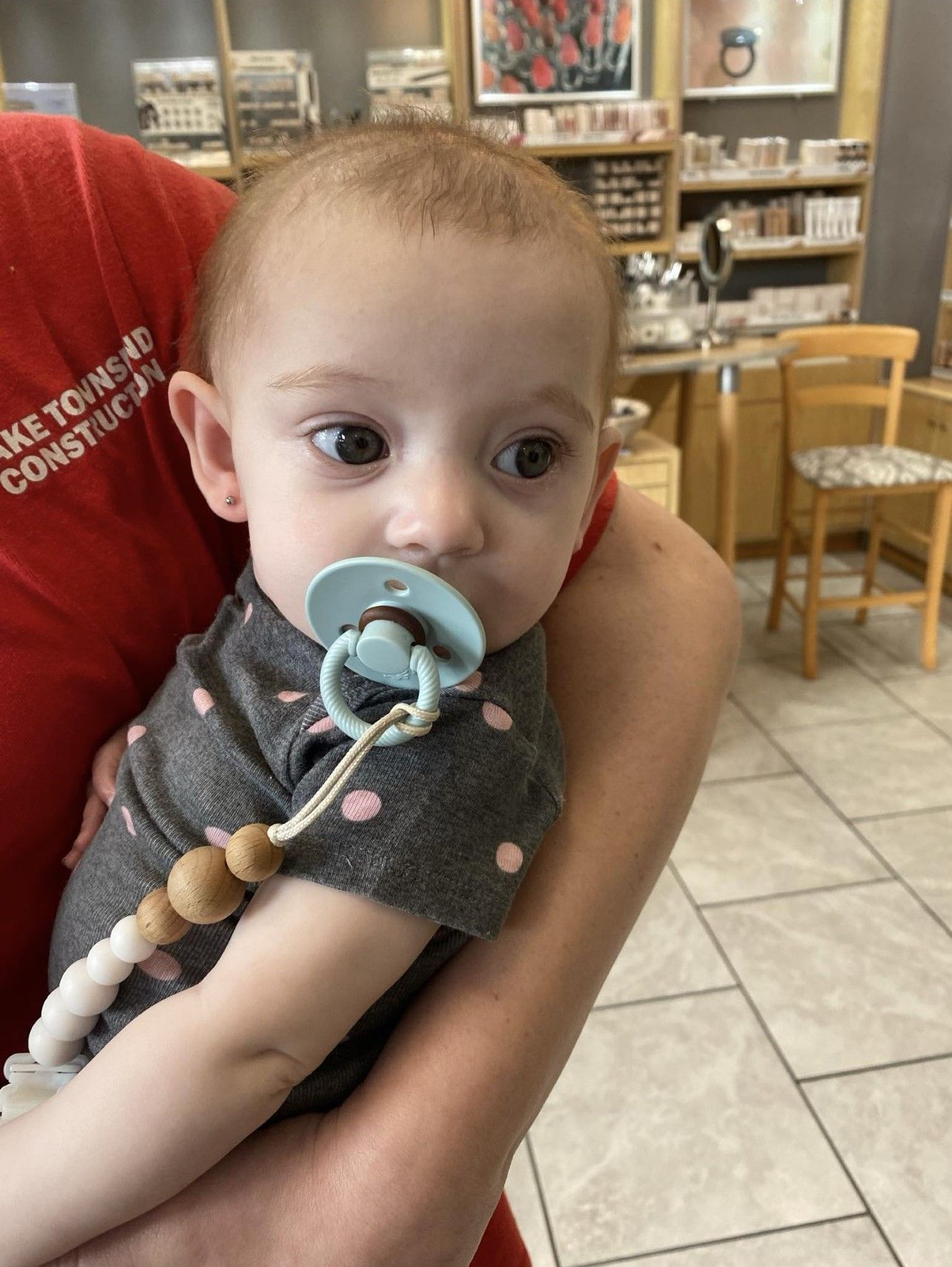 A woman is holding a baby with a pacifier in her mouth.