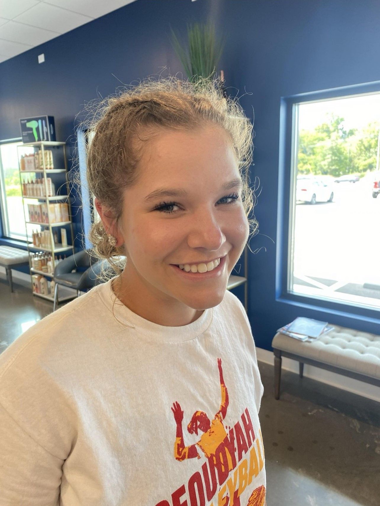 A woman in a white shirt is smiling in a room.
