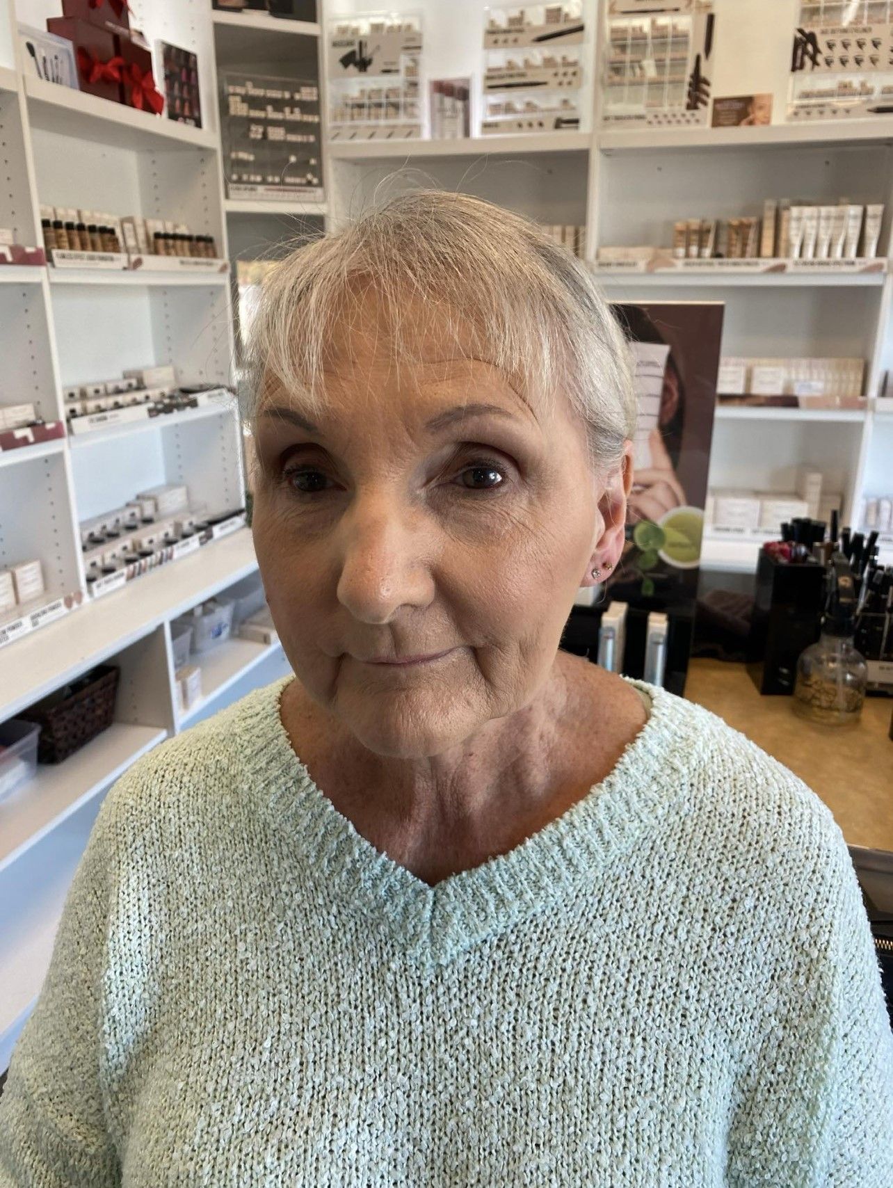 A woman in a green sweater is standing in a store.