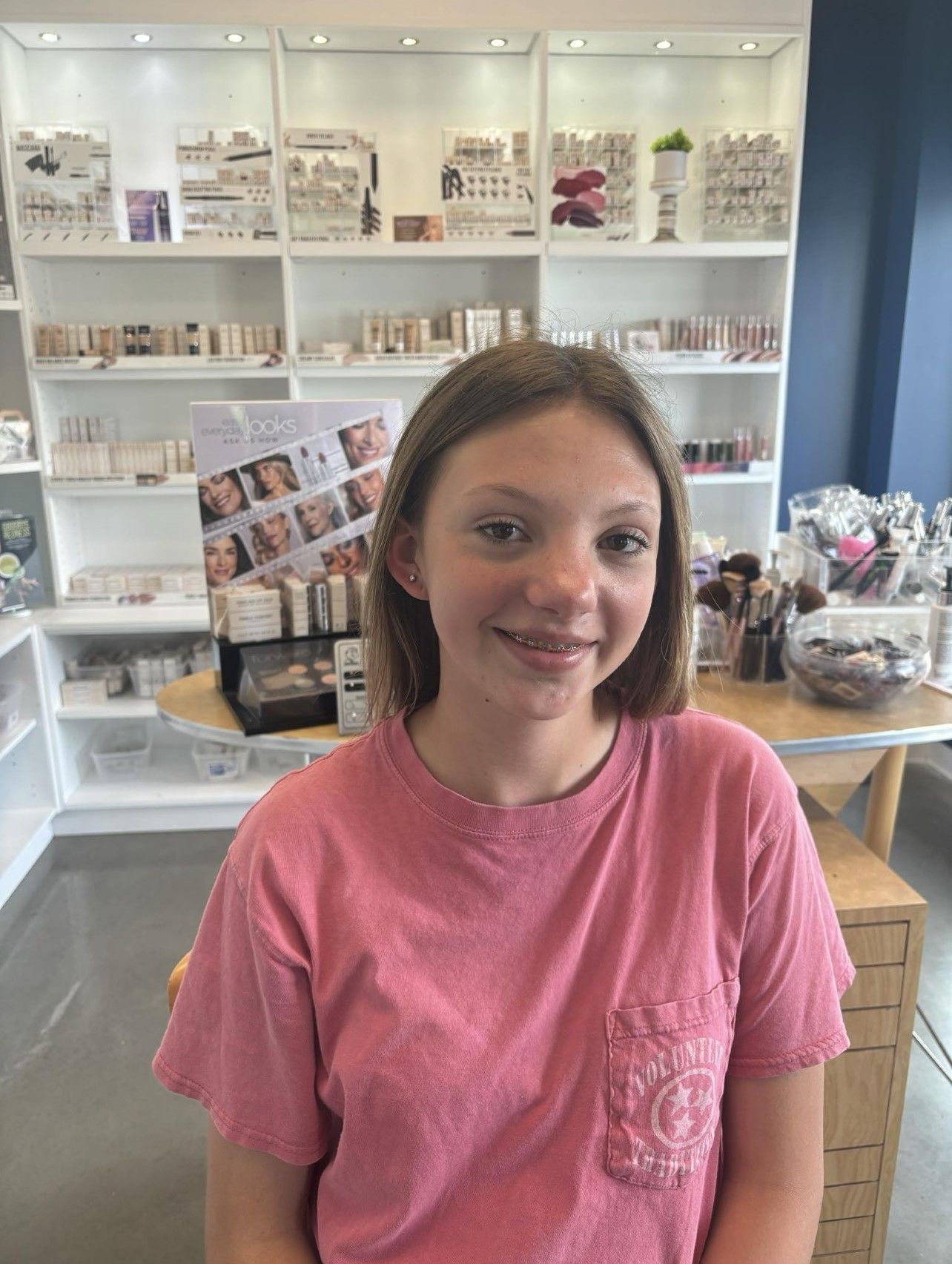A young girl in a pink shirt is standing in a store.