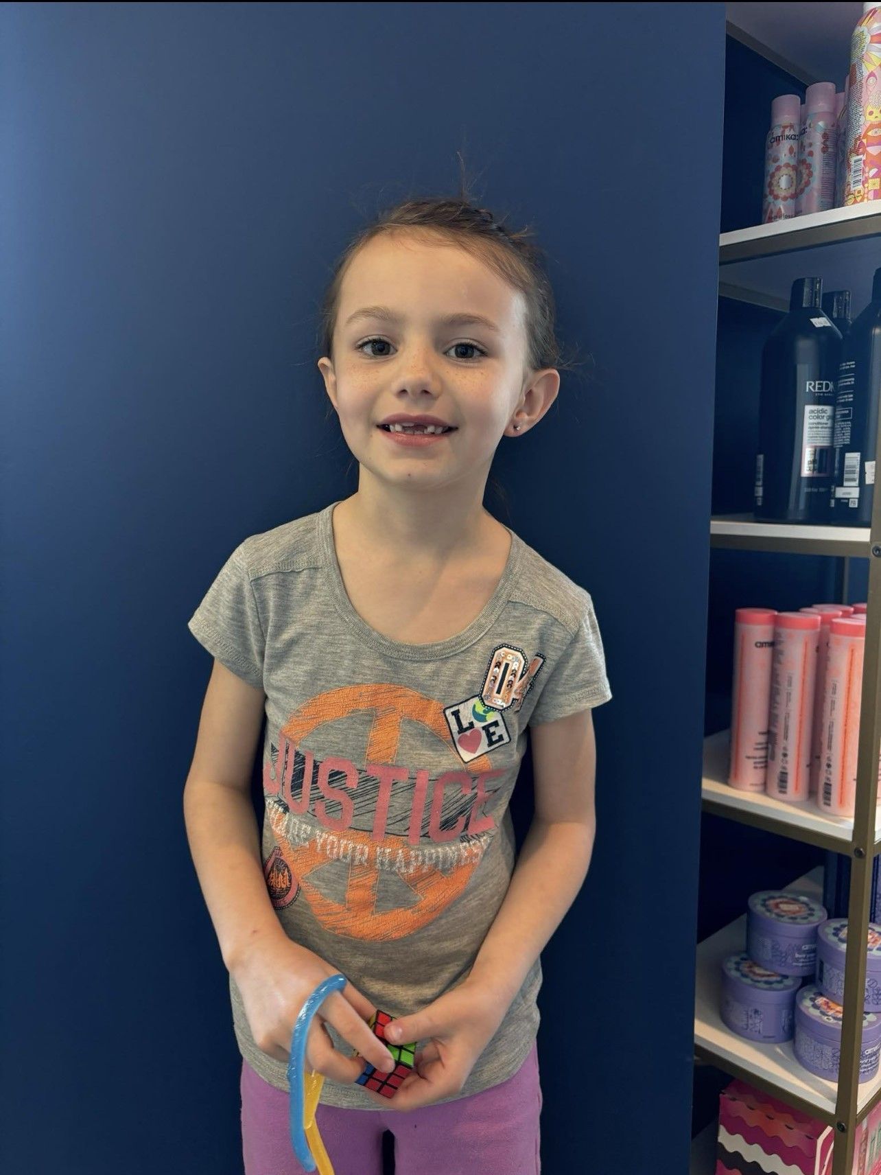 A little girl is standing in front of a shelf of hair products