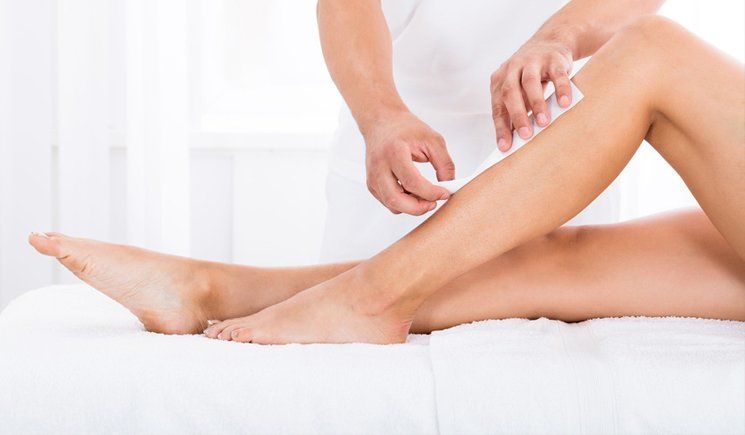 A woman is getting her legs waxed at a spa.