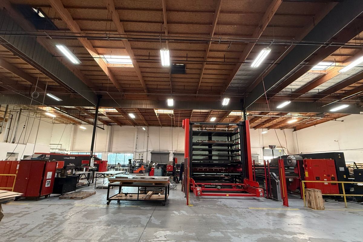 Warehouse interior with machinery and tools. Red and silver equipment against white walls and a wooden ceiling.
