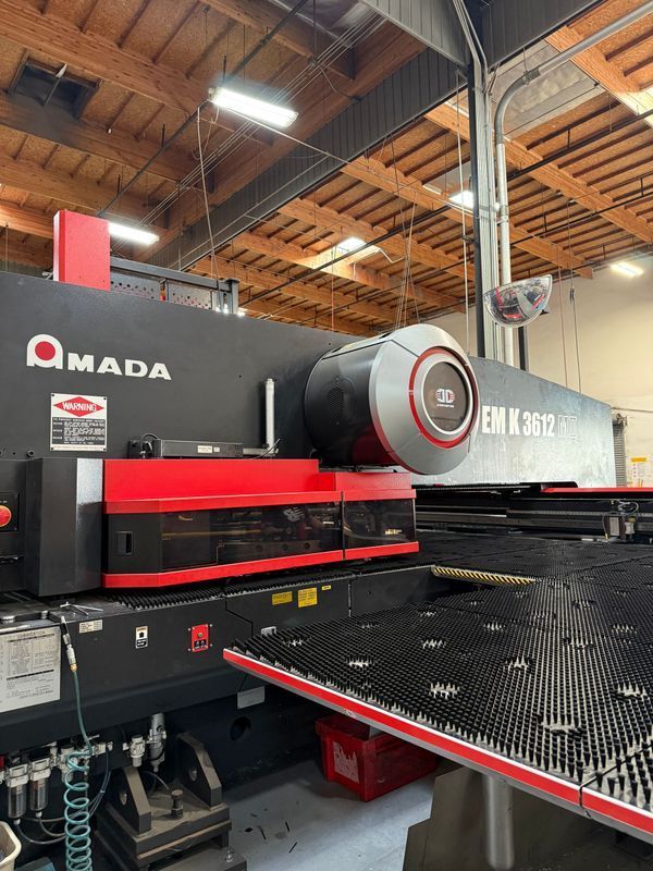 Amada EM K 3612 industrial punch press machine in a factory setting.