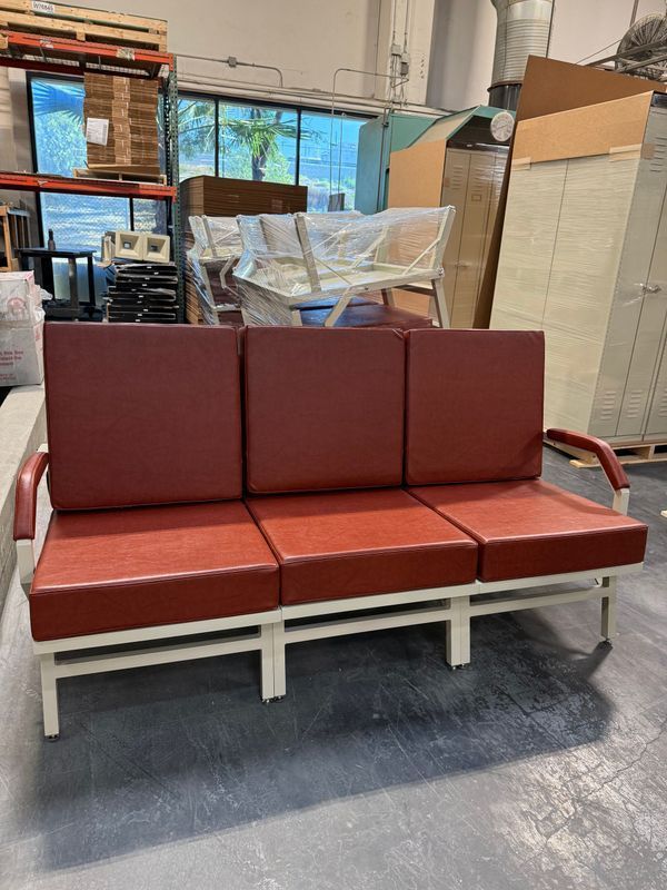 Red upholstered waiting room sofa with a white metal frame, in an industrial setting.