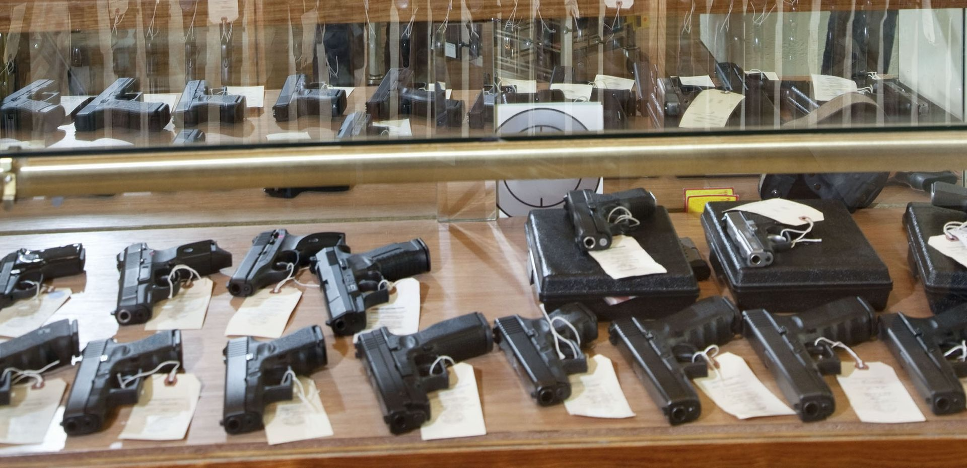 Guns displayed inside a glass case in what appears to be a gun store.
