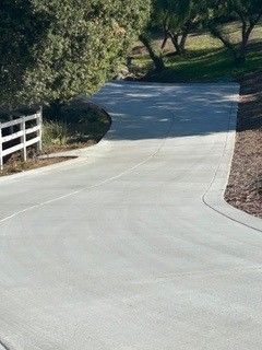 A concrete driveway with a white fence on the side of it.