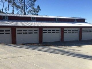 A row of garage doors on a building with a white roof.