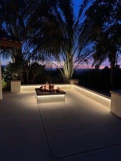 There is a fire pit in the middle of the patio at night.