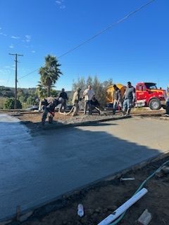 A group of construction workers are working on a concrete driveway.