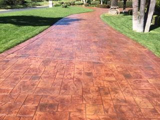A driveway leading to a house with a lush green lawn.
