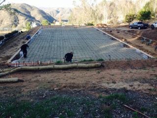 A couple of men are working on a concrete driveway.