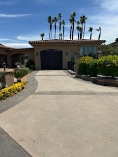 A driveway leading to a large house with palm trees on top.
