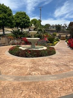 A fountain is surrounded by flowers and trees in a garden.