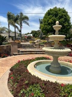 There is a fountain in the middle of a garden surrounded by flowers.