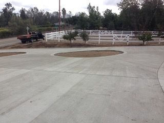 A concrete driveway with a white fence in the background.