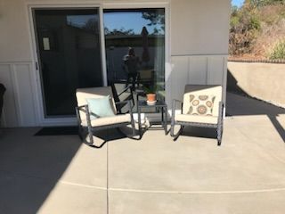 There are two rocking chairs and a table on the patio.