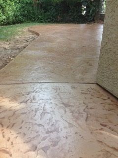 A concrete walkway leading to a house with trees in the background.